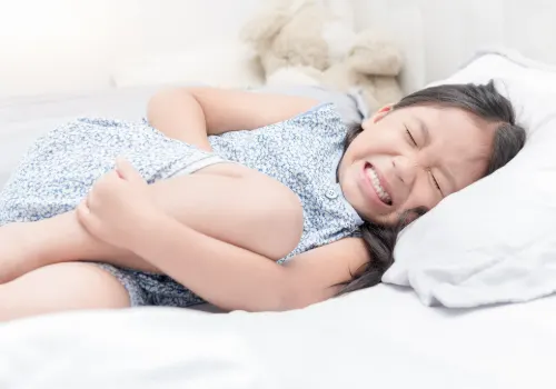 Young teen girl holding stomach in discomfort due to anxiety and stress.