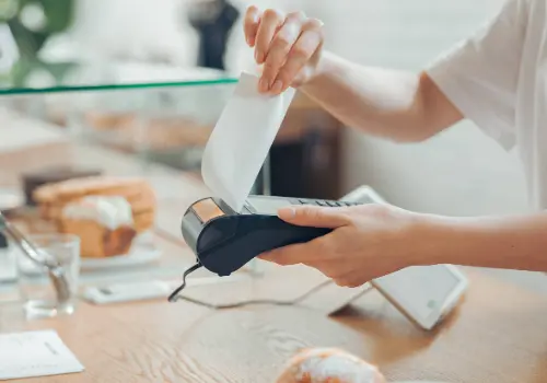 Cashier handing a thermal paper receipt, a common source of BPA and BPS exposure.