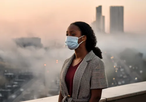 Young woman outdoors in a city, surrounded by air pollution—representing environmental lung cancer risk in non-smokers.