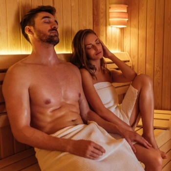A man and woman in a sauna, believing sweating more will help them recover from their fever.