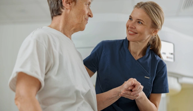 Radiology technologist assisting a patient after an MRI/CT scan procedure, both smiling, representing supportive and compassionate cancer care.
