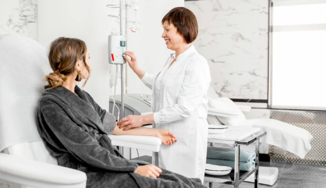 Female patient seated for dialysis treatment while a nurse prepares the dialysis machine, representing kidney care and nephrology services.