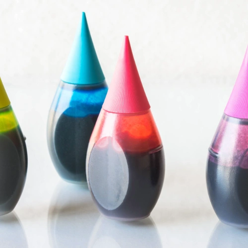 Four bottles of artificial food coloring in green, blue, red, and purple, commonly used for baking or decorating foods.