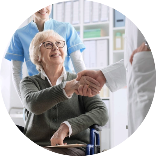 Geriatrician shaking hands with his elderly patient in a wheelchair.