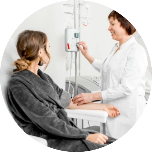 Female patient seated for dialysis treatment while a nurse prepares the dialysis machine, representing kidney care and nephrology services.