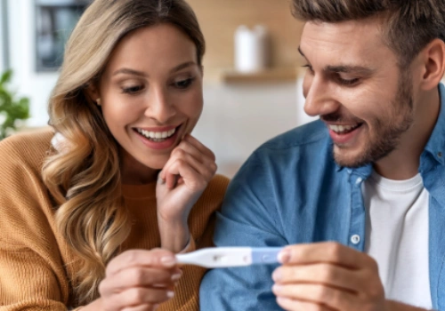 Happy couple staring at a positive pregnancy test.