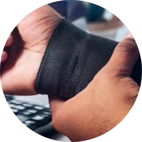 Close-up of a person’s wrist being gently held or wrapped, with a keyboard or computer mouse blurred in the background.