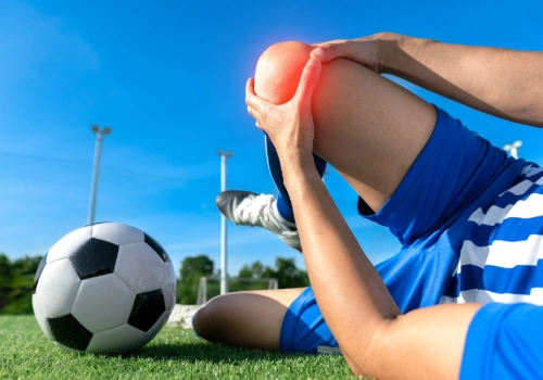 Young athlete holding knee after suspected ACL injury during sports activity.