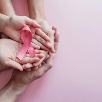 Hands holding a pink ribbon for breast cancer.