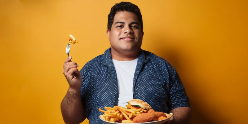 Person eating a meal high in saturated fats, which may contribute to elevated cholesterol levels