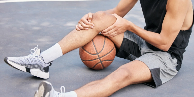 Basketball player holding his unstable knee in discomfort