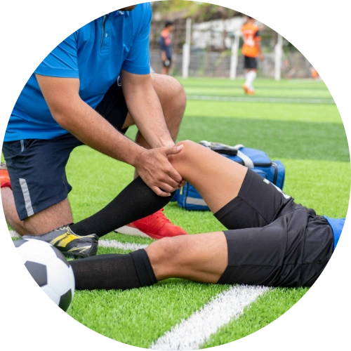 Soccer player getting his injured knee assessed by a trainer