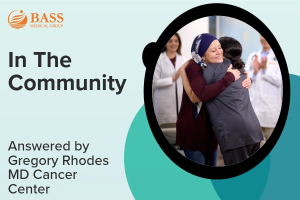 Two people embracing in a healthcare environment with text reading 'In The Community, Answered by Gregory Rhodes MD Cancer Center