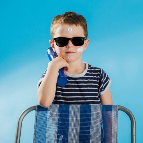 Kid wearing sunglasses and putting on sunscreen