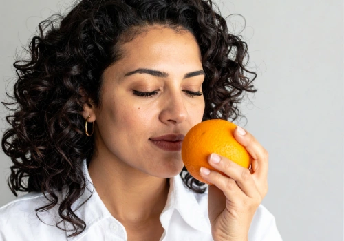 Woman smelling an orange close to her face
