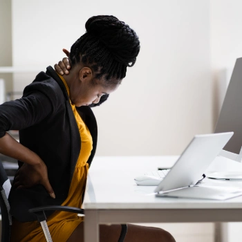 Woman with back pain from bad posture at her desk