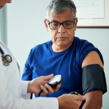 Doctor checking older patient's blood pressure