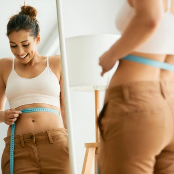 Woman measuring her weight loss with a measuring tape