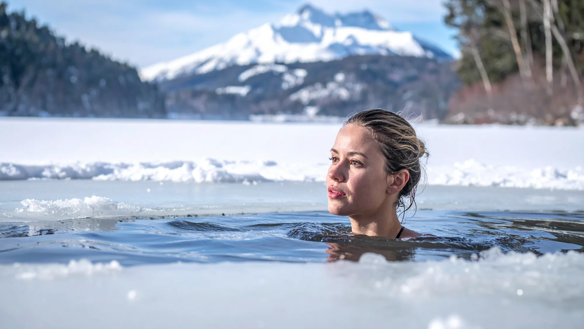 Woman performing a cold plunge by immersing in a slushy frozen lake