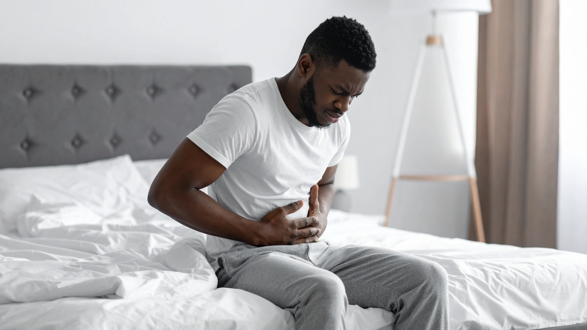 Man feeling nauseous in the morning in his bed