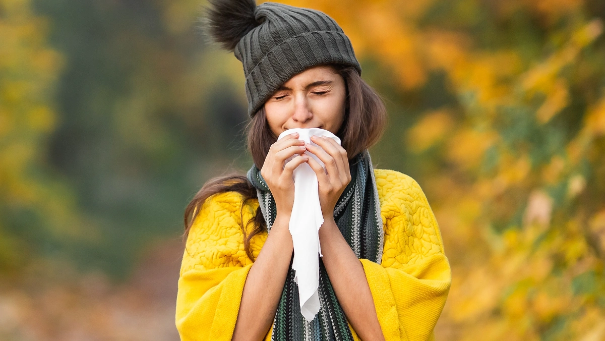 Woman outdoors in the East Bay experiencing seasonal allergy symptoms during spring pollen season, including sneezing and nasal irritation.