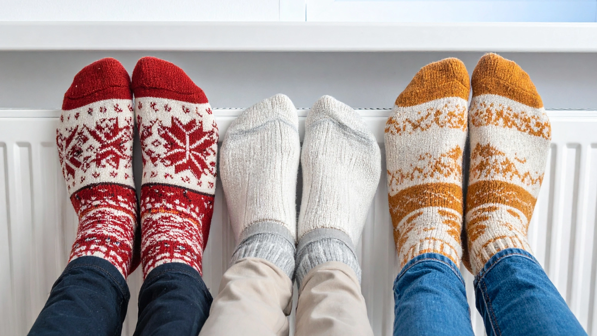 Three pairs of feet resting on a radiator to warm up.