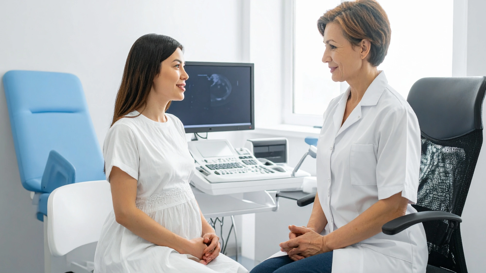 Woman speaking with an OB-GYN during a routine gynecologic visit in a medical office.