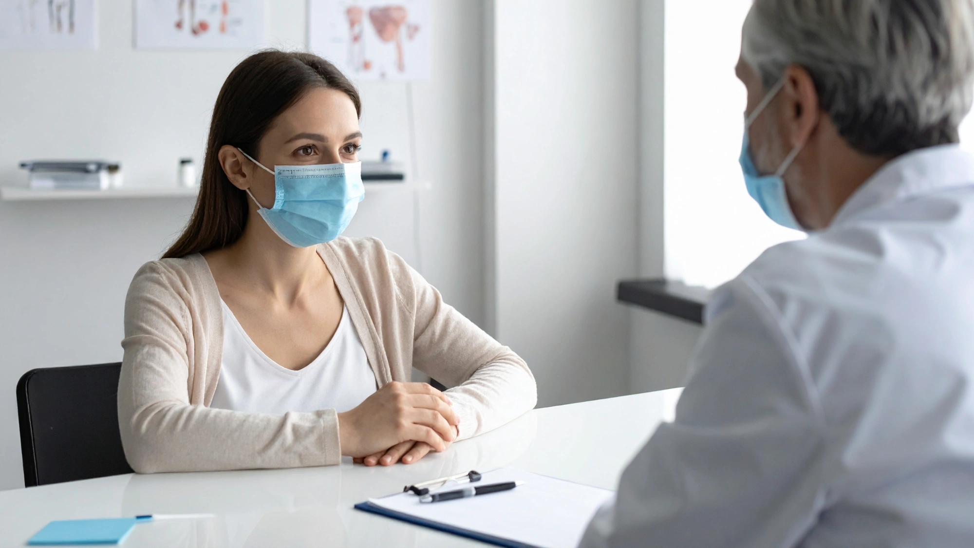 Patient wearing a mask while speaking with a doctor during a seasonal illness consultation.