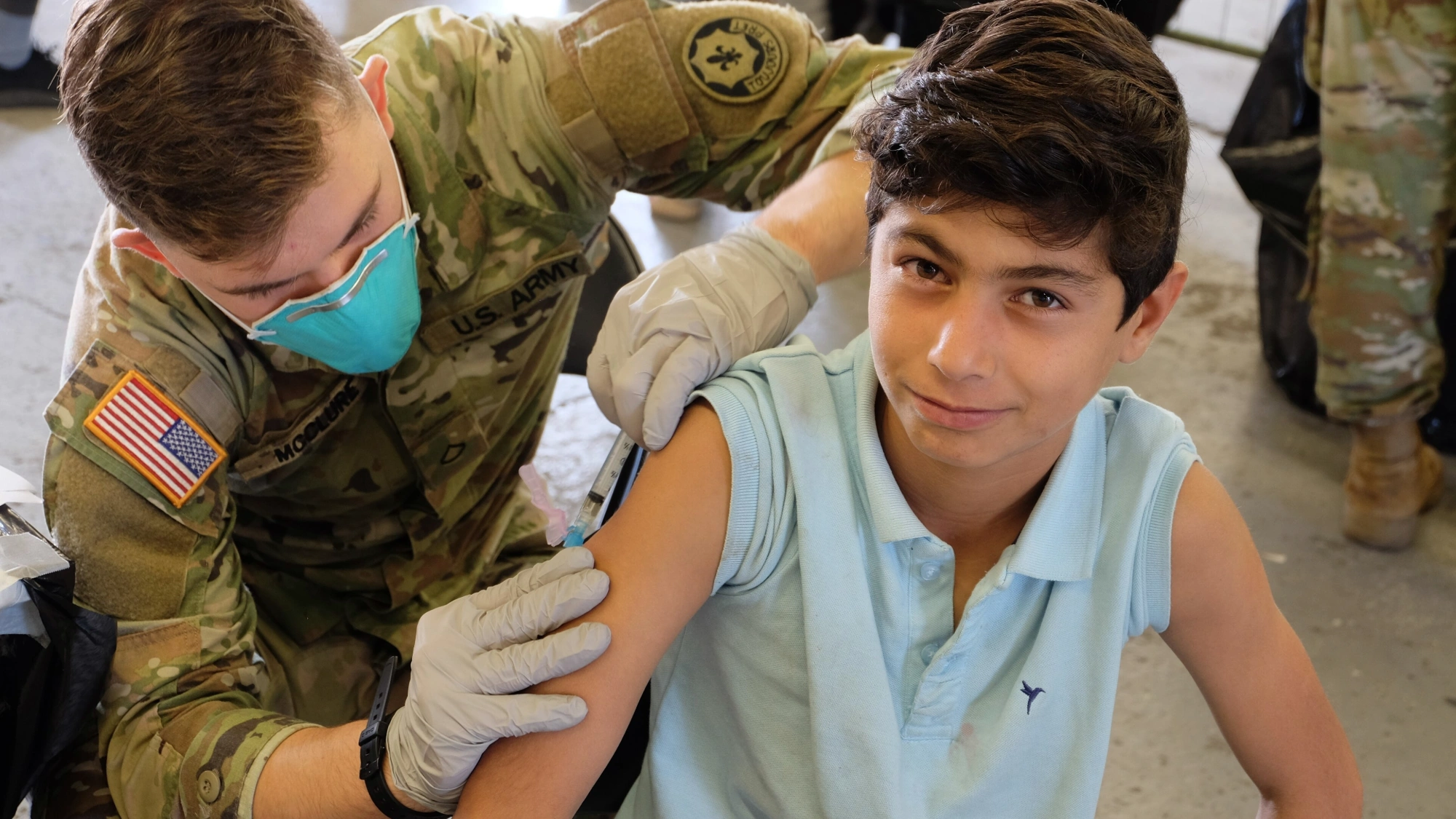 Army medic administering an MMR vaccine to an Afghan evacuee.