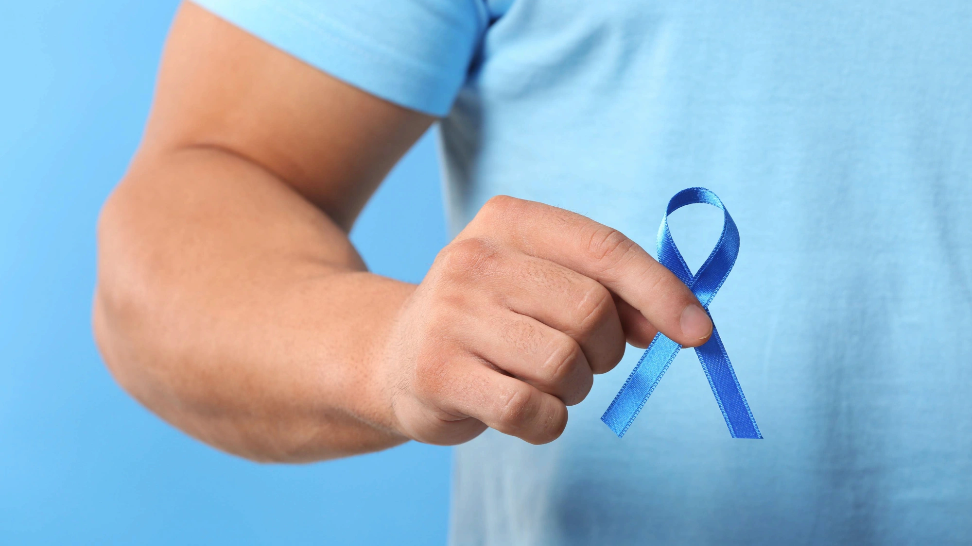 Man holding a blue ribbon for prostate cancer awareness month