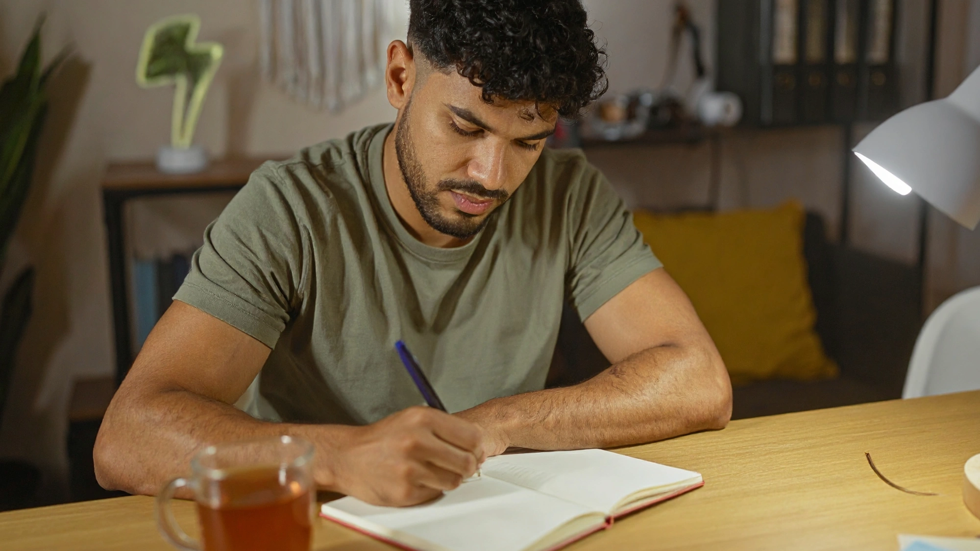 Young man journaling at a desk as part of a mental health and self-care routine.