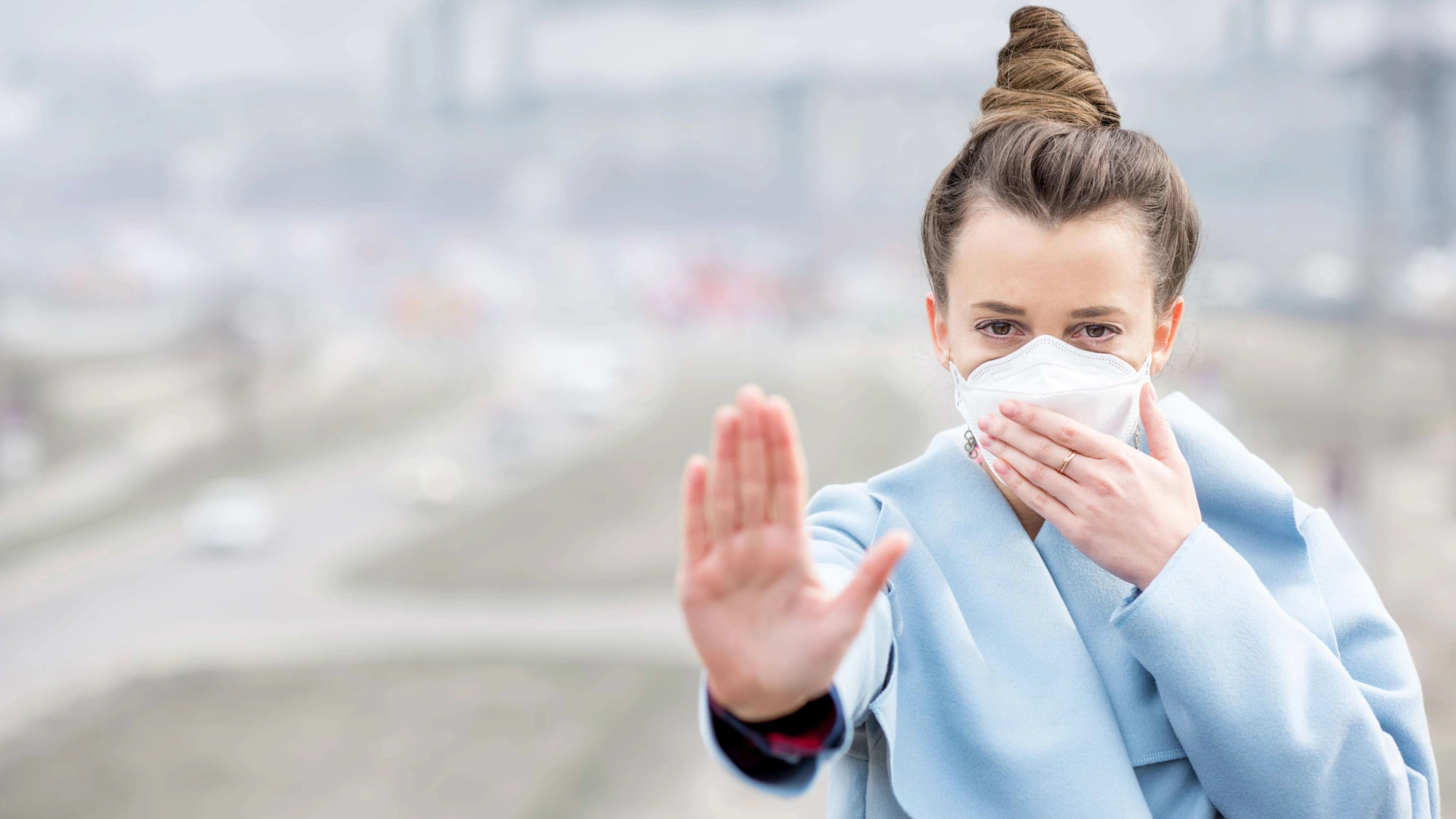 Young woman wearing a protective mask in a city with heavy air pollution and smog.