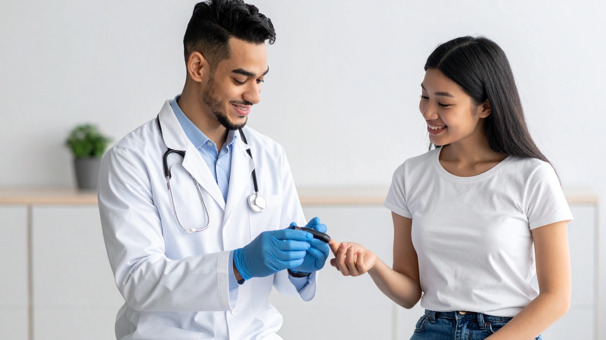 Doctor showing young diabetic girl how to use a blood sugar test