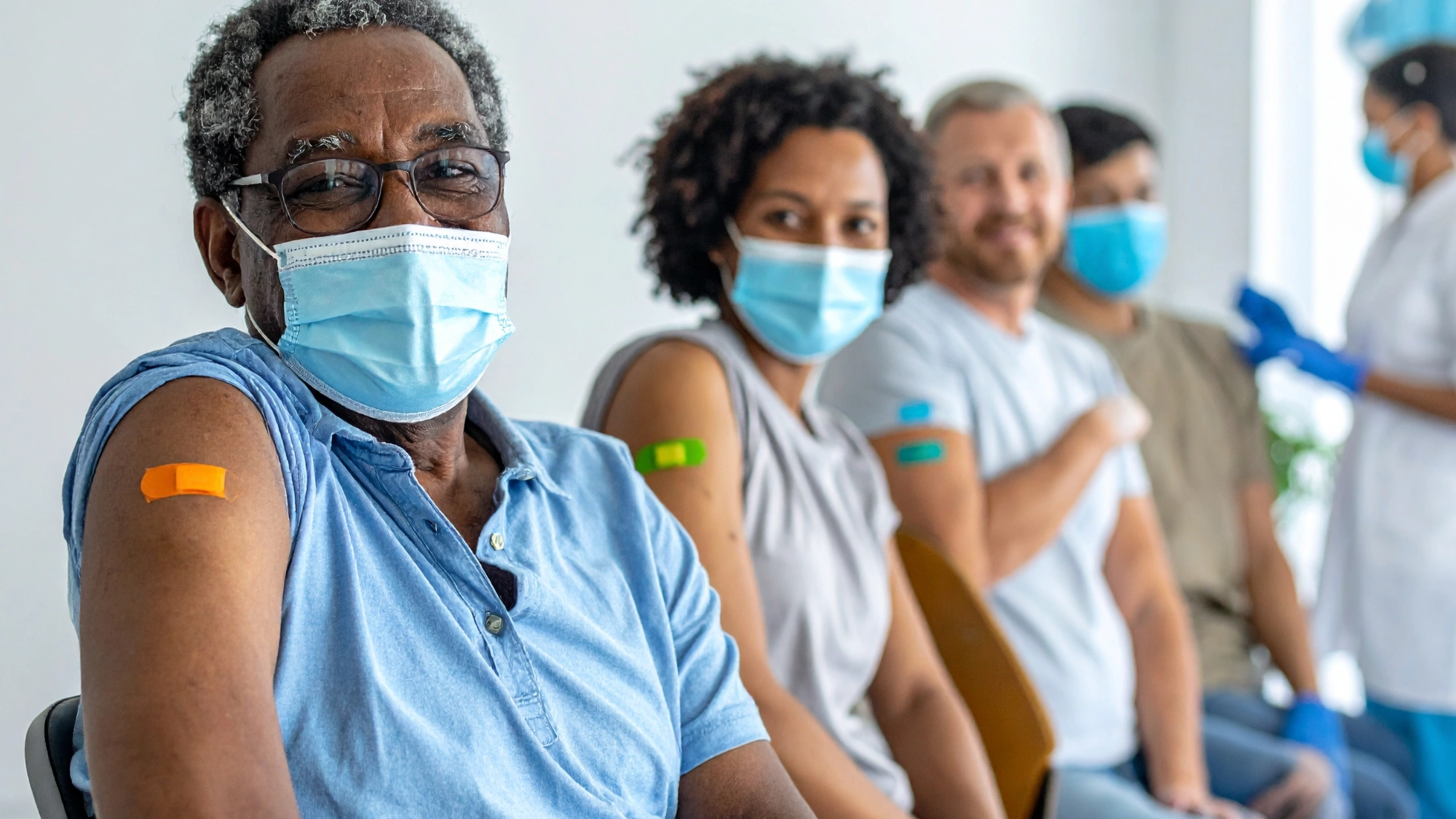 A group of adults with bandages on their arms after receiving the seasonal flu shot