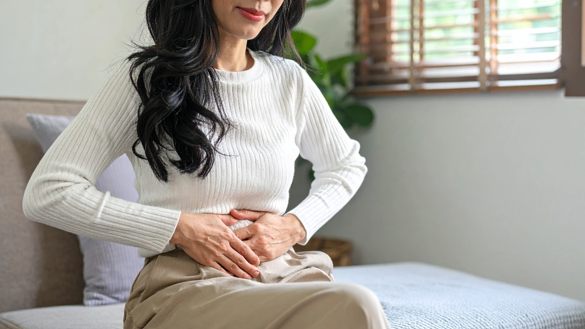 Woman holding her stomach due to bloating and abdominal discomfort.