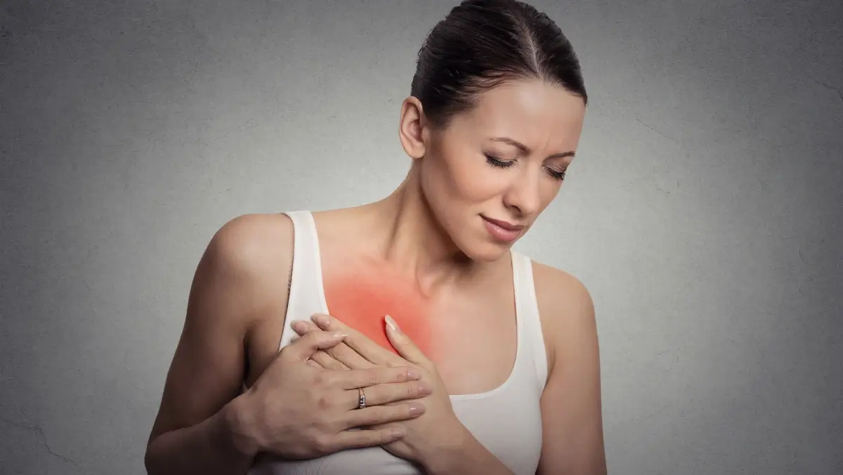 Woman touches her breast in discomfort, with a red highlight showing tenderness or pain, illustrating breast soreness linked to birth control.