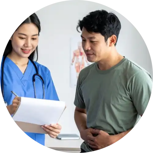 Hernia surgeon reviewing medical information with a male patient holding his lower abdomen during a consultation.