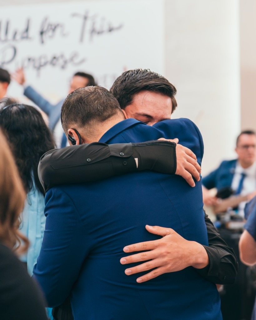 Two men embracing during fellowship at Voice of Truth Tabernacle