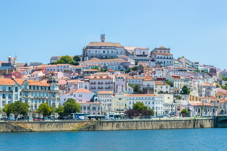 Vue panoramique de Coimbra au Portugal avec ses bâtiments historiques et ses toits en tuiles rouges dominant la vallée du Mondego