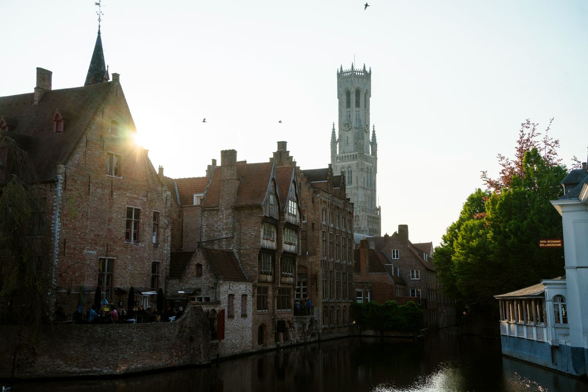 Couple walking along the canals of Bruges with historic buildings in background Couple walking along the canals of Bruges with historic buildings in background
