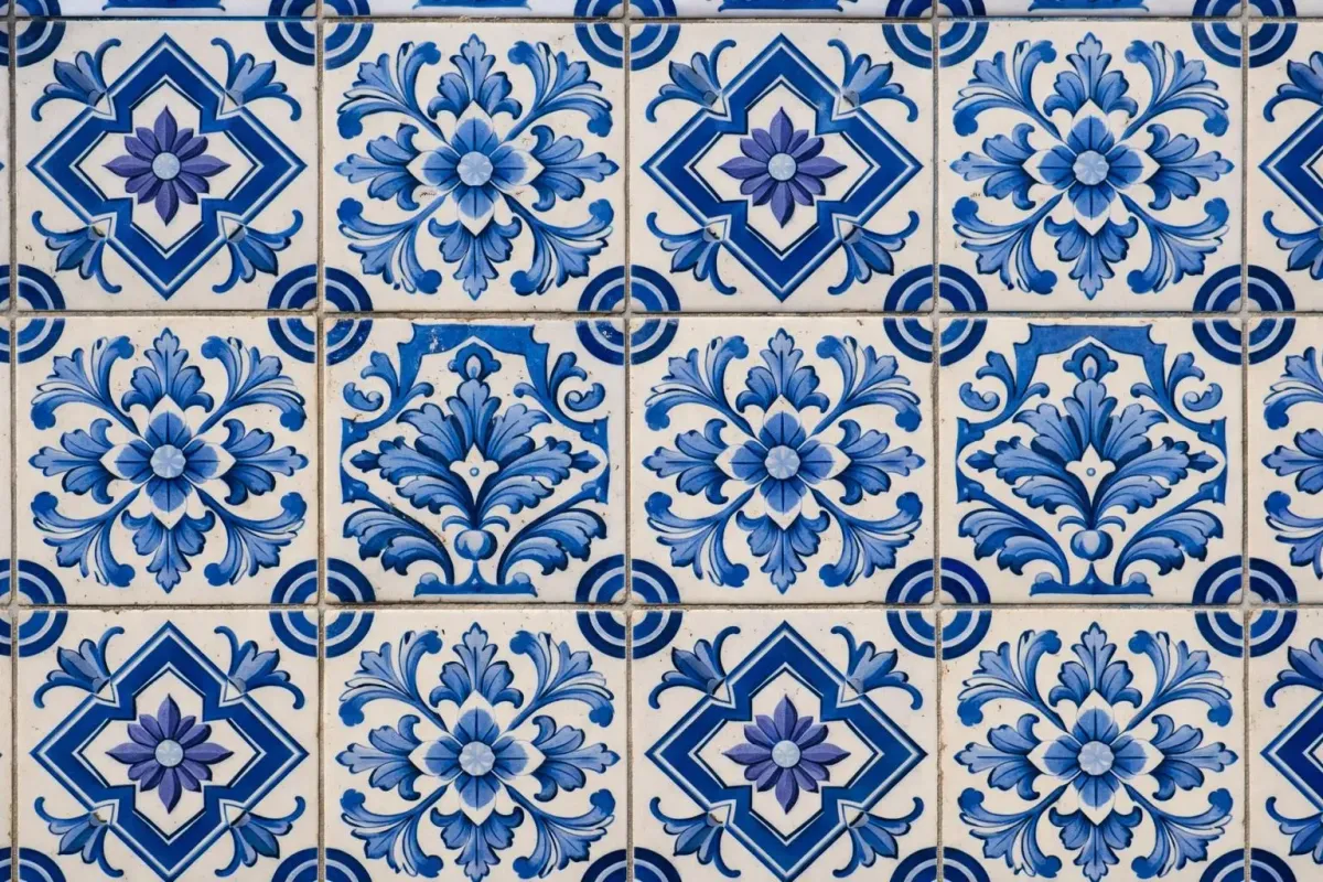 Close-up view of traditional Portuguese azulejo tiles in blue and white patterns on a historic building facade in Lisbon, showing intricate hand-painted geometric and floral designs, natural daylight