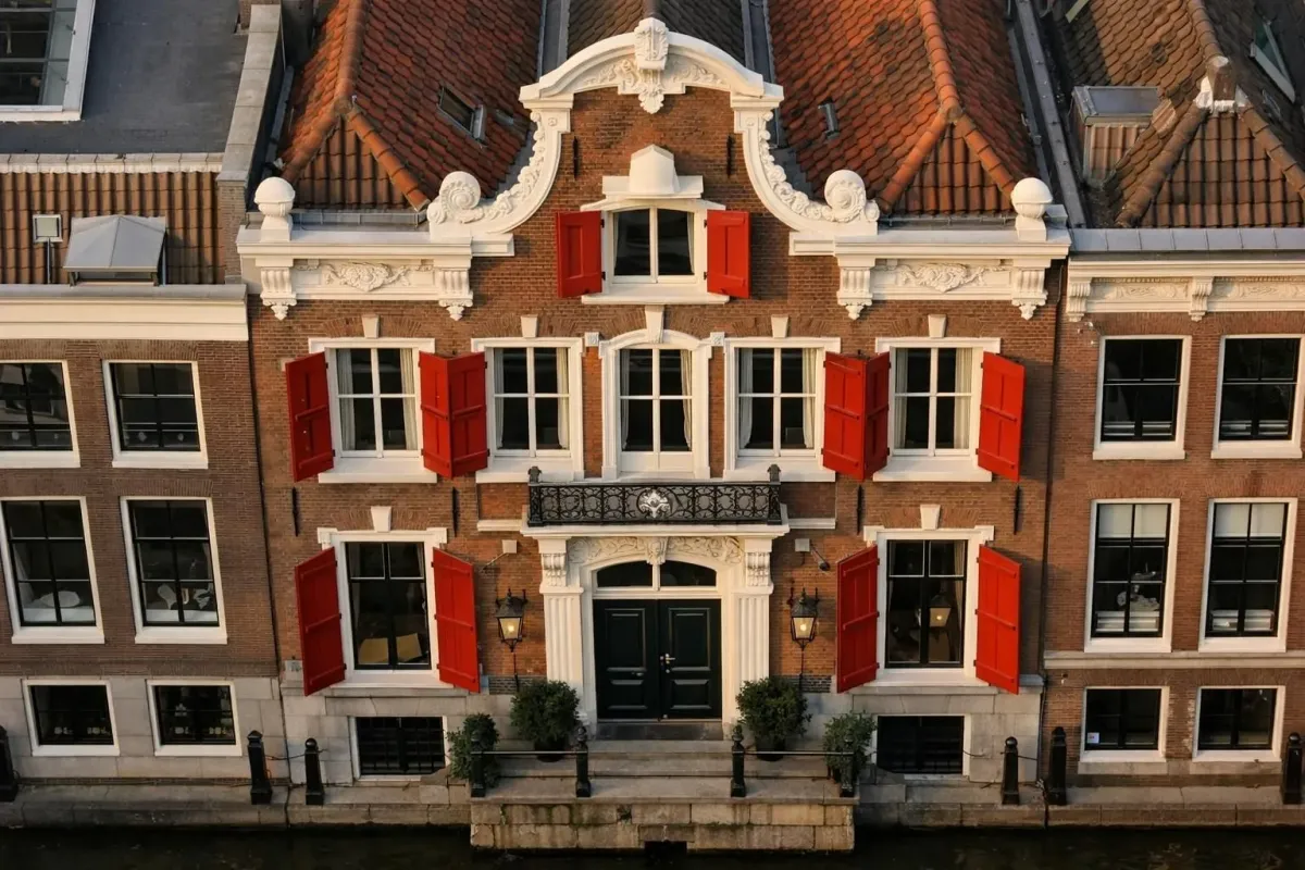 Elegant canal house facade on Keizersgracht in Amsterdam with historic 17th-century Dutch architecture, narrow windows, and canal reflection at golden hour, no text visible