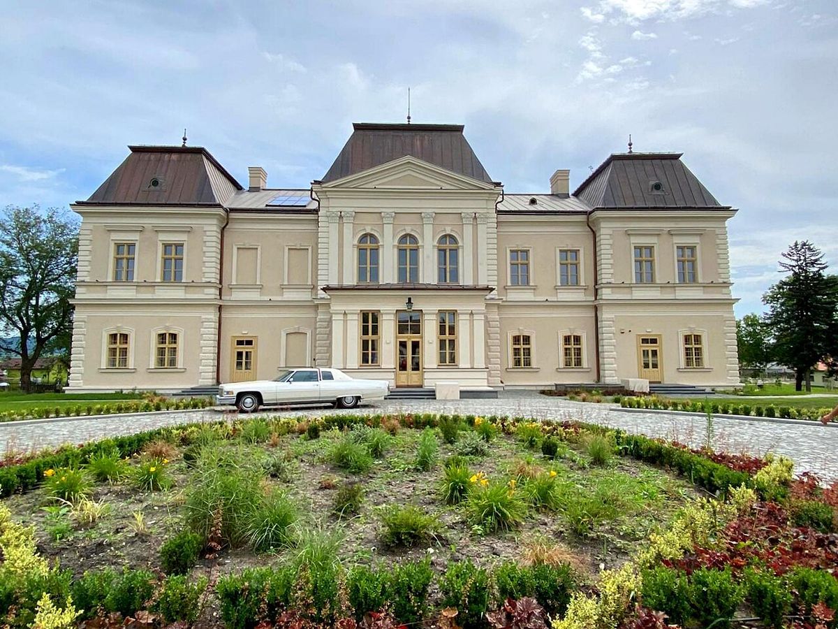 A man in a denim jacket carefully chiseling a stone block.