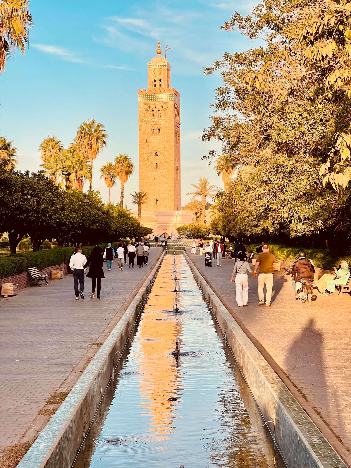 Colorful traditional Moroccan courtyard riad with blue tiles, fountain, and winter sun filtering through orange trees, authentic local architecture in Marrakech medina