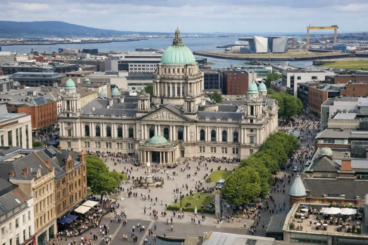 Aerial view of compact Belfast city center showing Victorian City Hall dome surrounded by walkable streets and nearby Titanic Quarter, with pedestrians visible on sidewalks