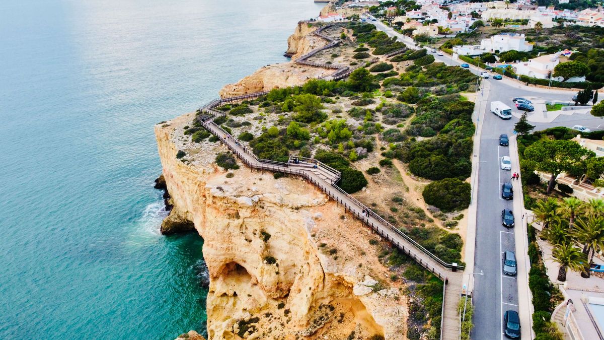 Picturesque coastal town, vibrant buildings, turquoise waters, boats, and beachgoers.