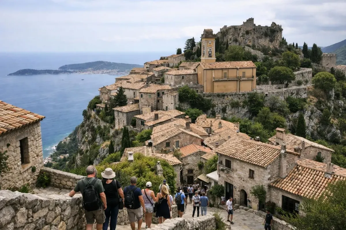 Charmant village médiéval perché sur une colline rocheuse de la Côte d'Azur, avec des visiteurs explorant les ruelles pittoresques