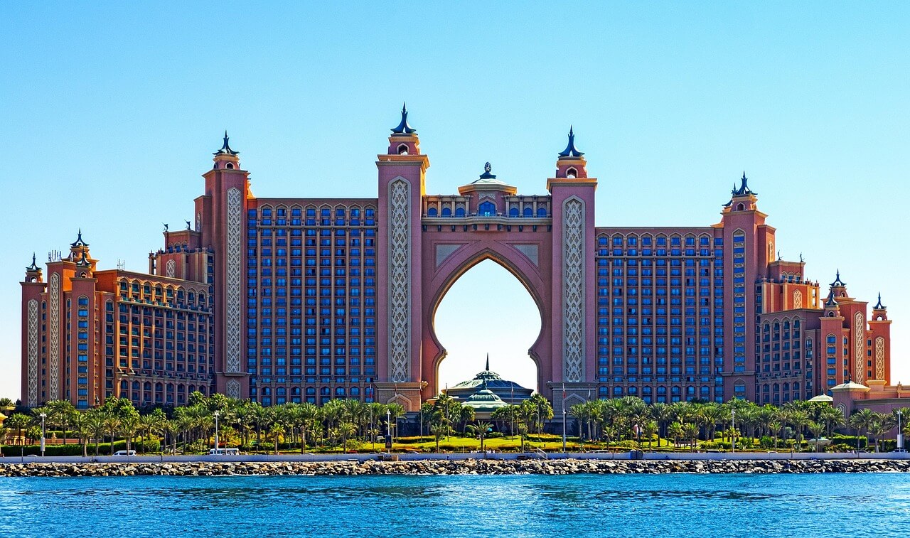 Vue panoramique de Dubaï avec ses gratte-ciels emblématiques illuminés au coucher de soleil, reflets sur l'eau du golfe Persique