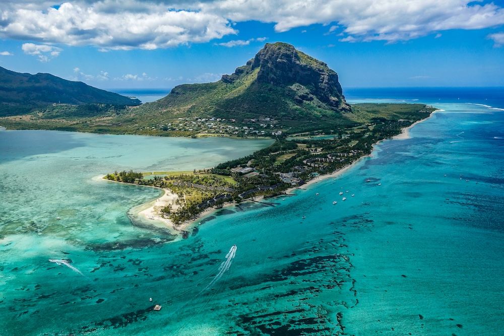 Plage tropicale de l'île Maurice avec sable blanc et eaux turquoise sous un ciel dégagé, symbolisant une destination paradisiaque de l'océan Indien