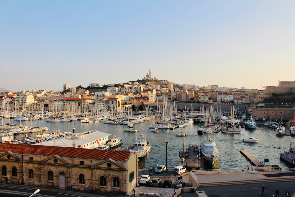 Port animé de Marseille avec bateaux amarrés, reflets méditerranéens et architecture portuaire typique de la ville